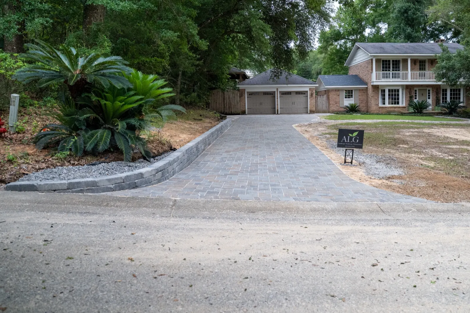 Finished paver driveway curving past palm landscaping to a two-car garage in Baldwin County, Alabama
