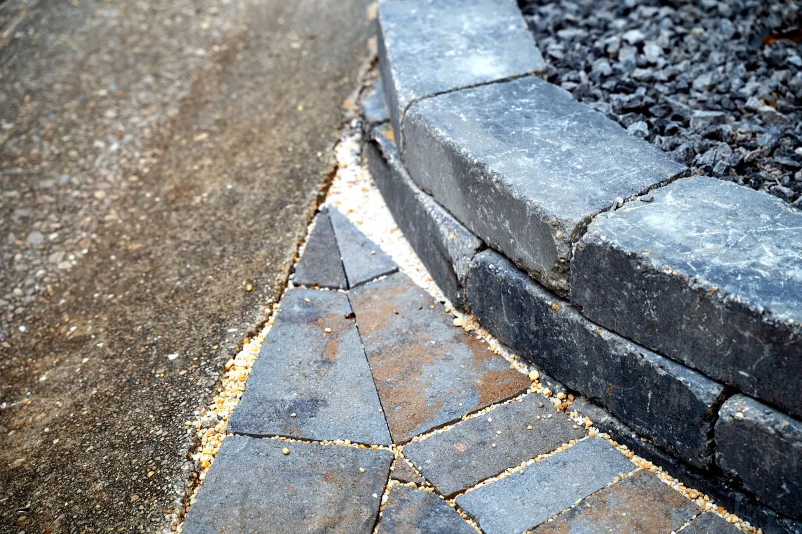 New paver driveway with block retaining wall leading to a two-car garage at a brick home in Baldwin County, Alabama