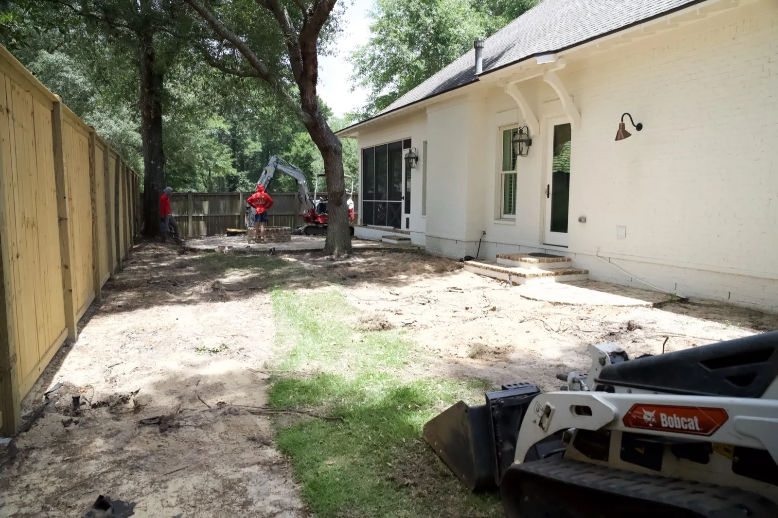 Torn-up backyard mid-demolition with skid steer behind a home in Point Clear, Alabama