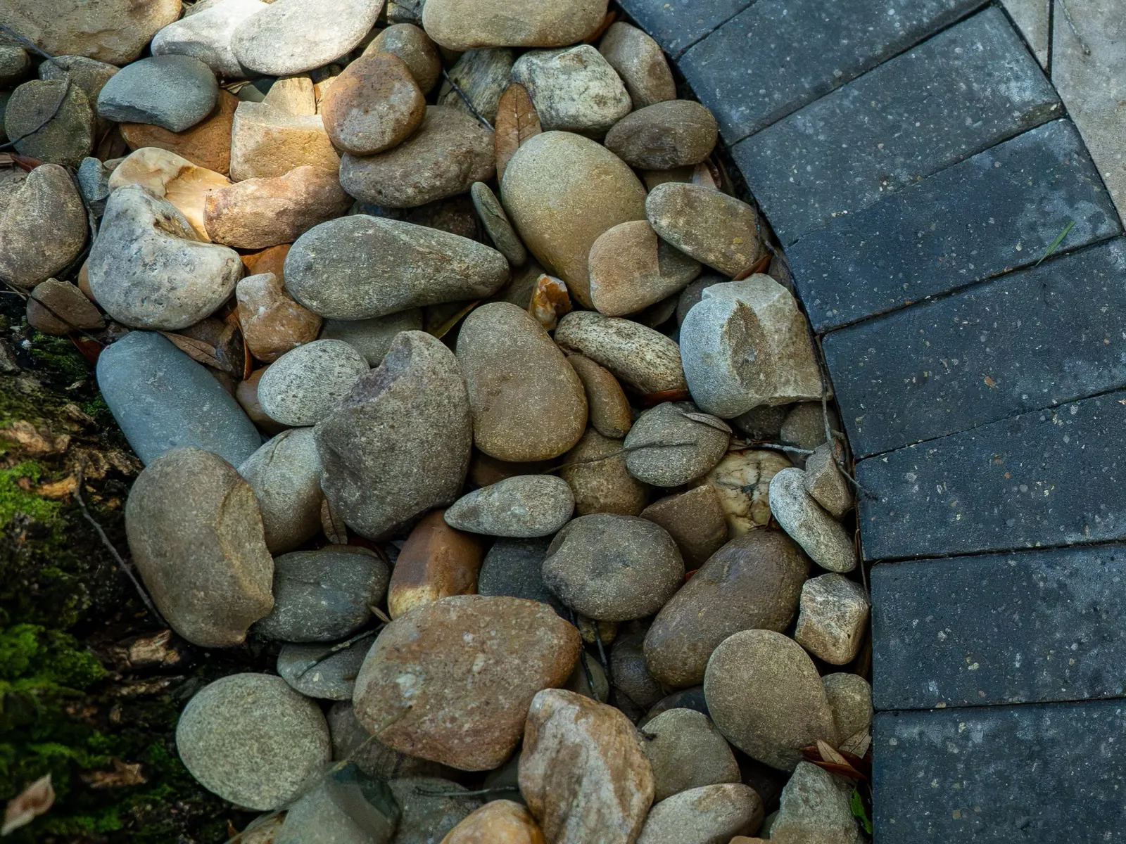 Close-up detail of a river-rock drainage border along a paver patio edge at a Point Clear, Alabama home
